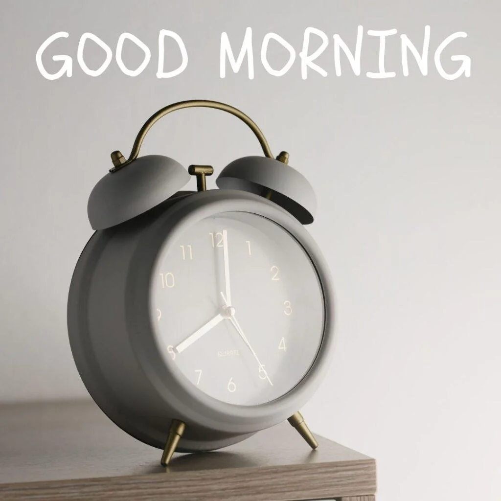 Grey clock on the grey table, above the clock good morning is placed