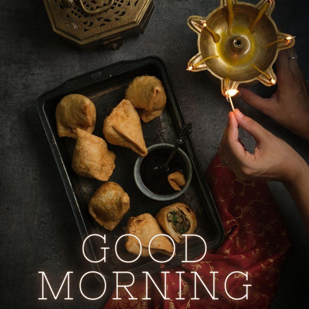 samosa and chutney on the black plate, beside the diya lighting by hand. good morning quote also placed