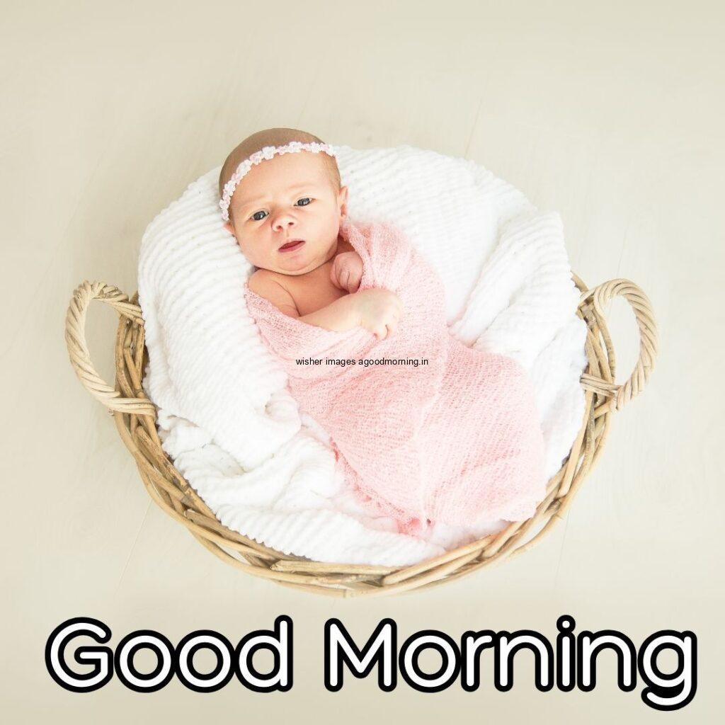 Baby girl on the bed with white clothe in basket good morning quote is placed