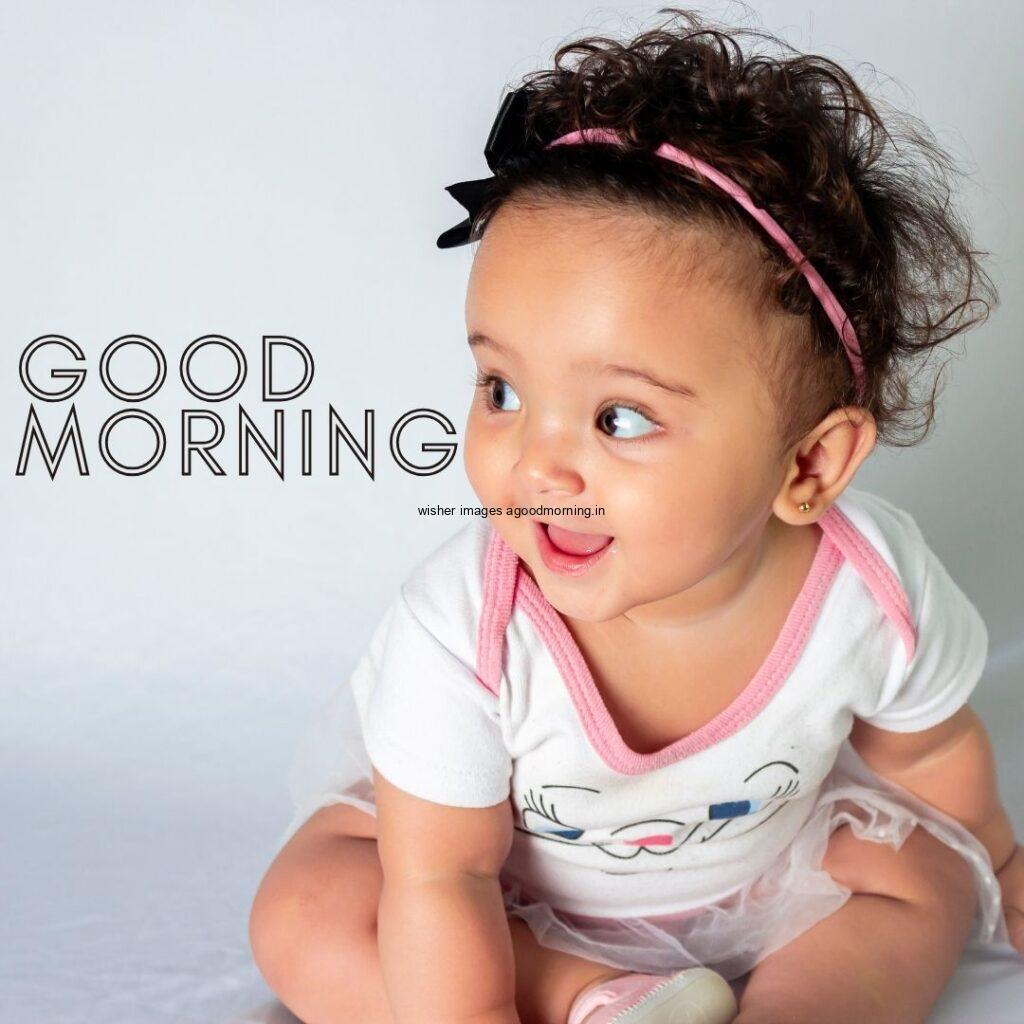 Baby girl wearing the white t-shirt clothes behind the grey background good morning quote is placed