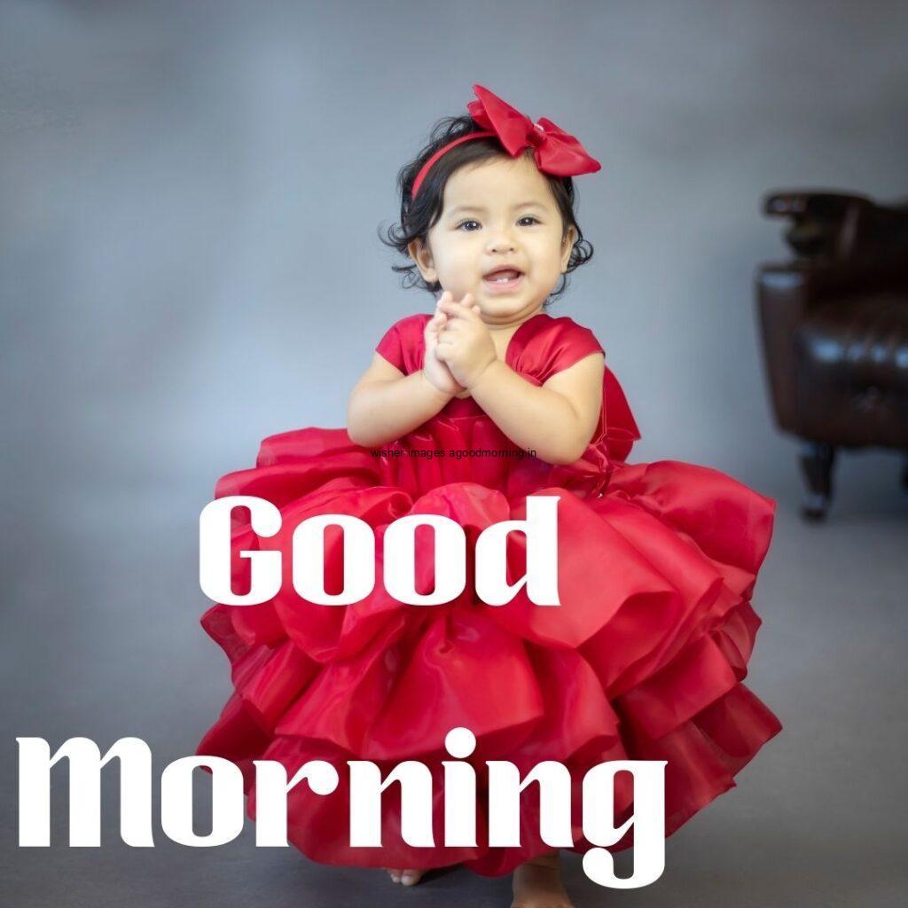 Baby girl wearing the red frook with grey background good morning quote is placed