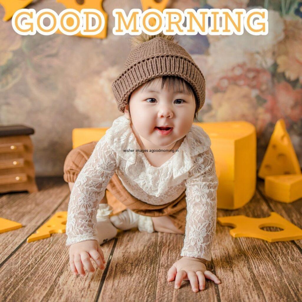 Baby sitting with his toys behind the yellow toys is setup good morning quote is placed