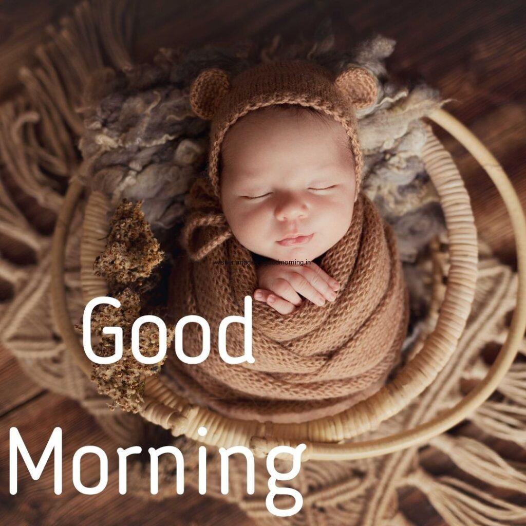 Baby sleeping in the Brown basket with wearing the hand band good morning quote is placed