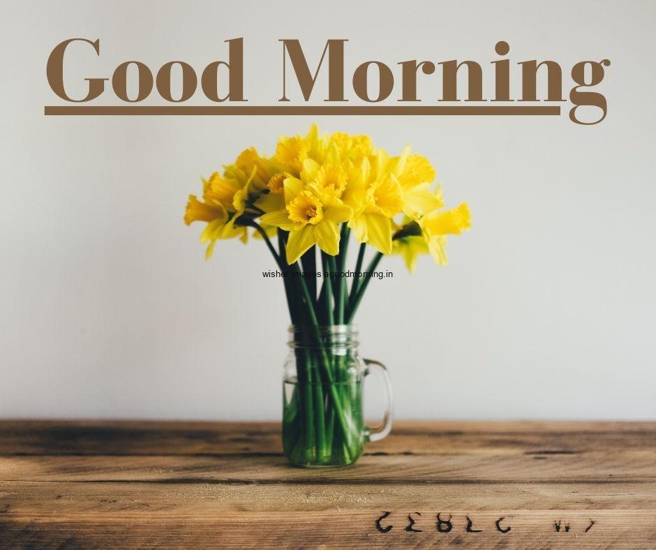 glass vase with leaf with yellow flowers good morning flower images table and chair with window view is visible