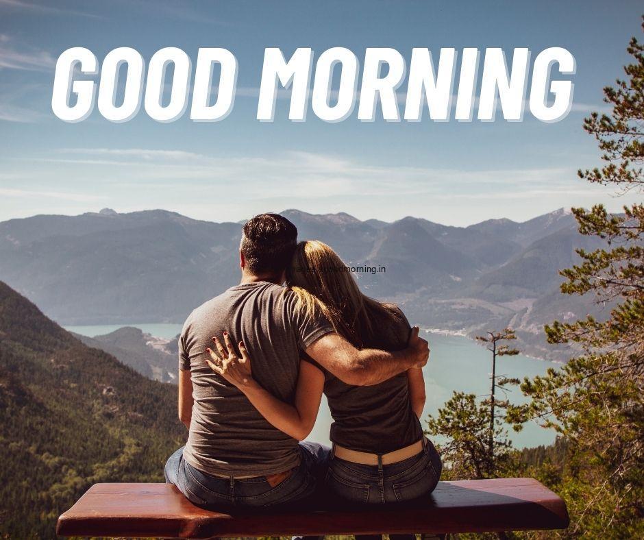 Good morning quote is placed with white colour couple siting on rock and see the sky and trees