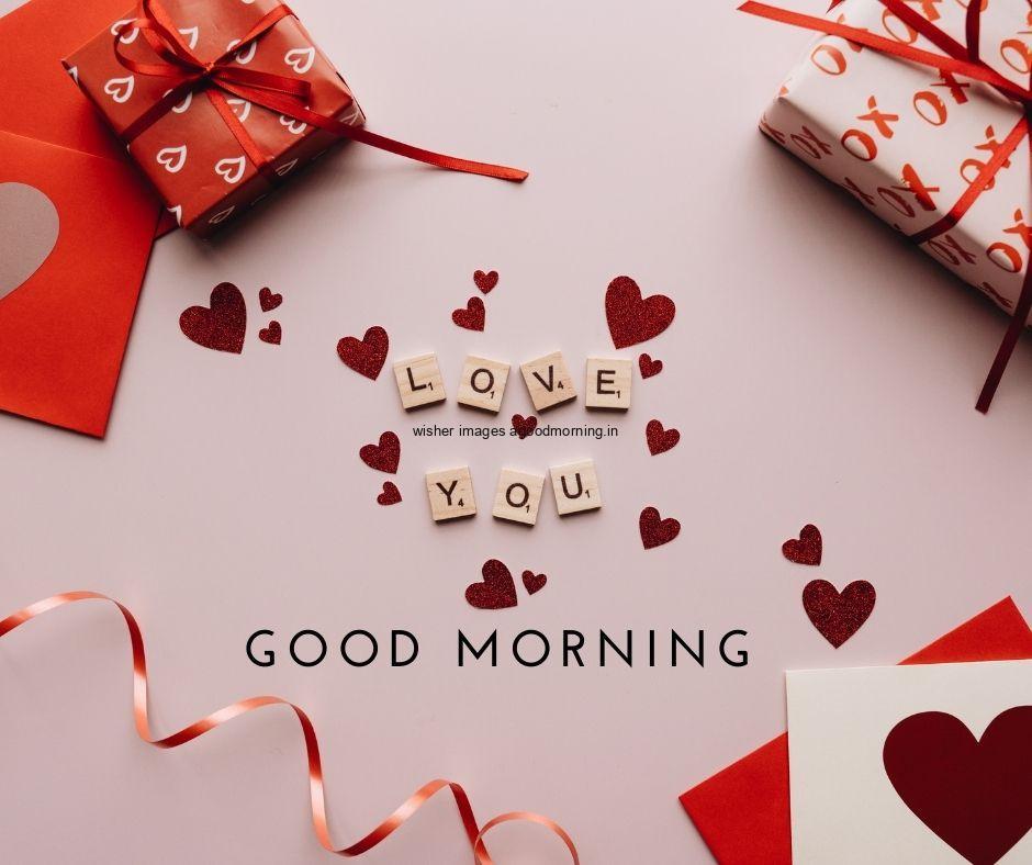 Good morning quote is placed with white gift box pink background with ribbon many heart is placed