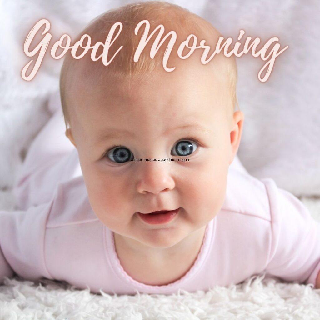 Smile baby seen in front and pink dress is wearing, the baby eyes is blue good morning quote is placed