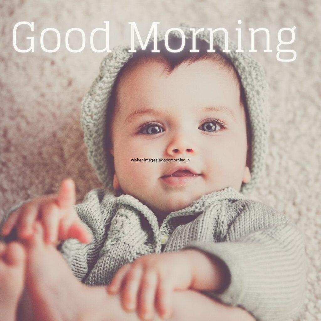 smiling baby seen in front and grey dress is wearing good morning quote is placed