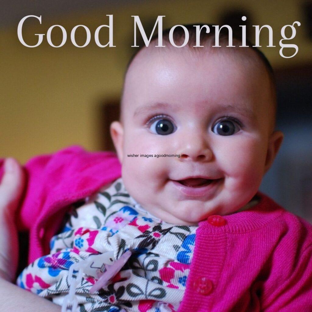 smiling baby seen in front and pink dress is wearing good morning quote is placed