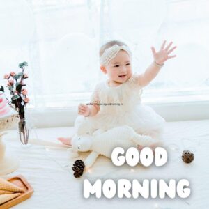 50+ Free Good Morning images with baby girl for your loved ones 14 white dress wearing the baby girl beside the girl flowers is setup good morning quote is placed