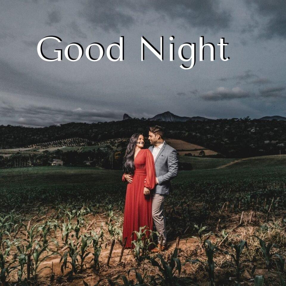 couople hug eachother in the night girl wearing red dress and men wear the grey beautifull background with good night placed on the top good night image